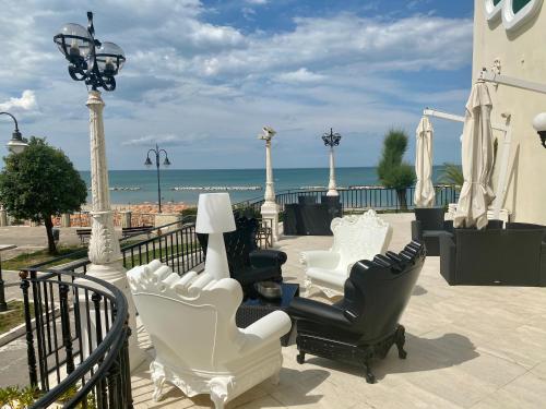 a group of chairs and lamps on a balcony with the beach at Grand Hotel Michelacci in Gabicce Mare