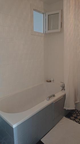 La salle de bains est pourvue d'une baignoire blanche et d'une fenêtre. dans l'établissement L'Amaryllis, beau T4 contemporain et lumineux en Centre Ville 3 étoiles, à Sète