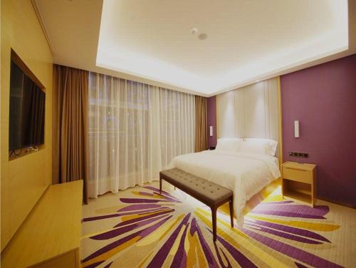 a bedroom with a bed and a flat screen tv at Lavande Hotel Heyuan Longchuan in Longchuan