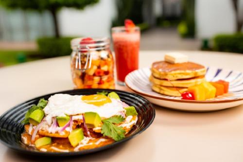 two plates of food on a table with pancakes at Hotel Horizon & Convention Center in Morelia