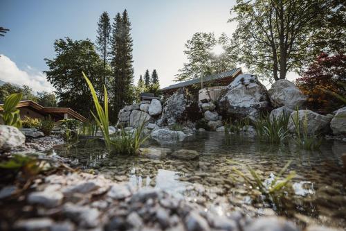 a pond in a garden with rocks and a house at Gästehaus Richter in Grainau