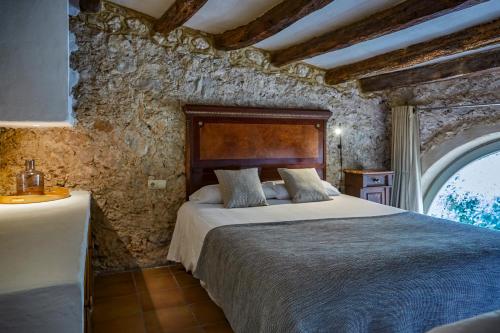1 dormitorio con 1 cama en una pared de piedra en Casa Olivo at Masia Nur Sitges, Adults only, en Canyelles