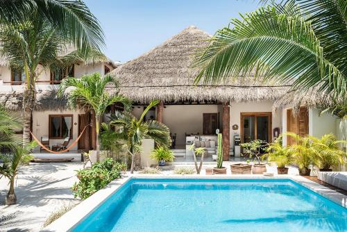 a villa with a swimming pool in front of a house at Tierra del Mar Hotel - Adults Only in Holbox Island