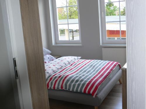łóżko w pokoju z dwoma oknami w obiekcie Apartament w Węgorzewie w Węgorzewie