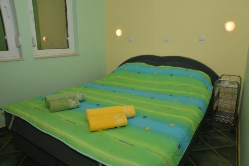 a bed with green sheets and yellow pillows on it at Rooms and Apartaments De Niro in Trpejca