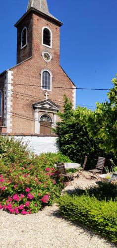 a building with a clock tower with two chairs and flowers at Wetterdelle in Heers