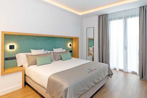 a bedroom with a large white bed with green headboard at Apartamentos Ardales Premium in Ardales