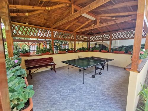 eine Tischtennisplatte in einem Pavillon mit einer Bank in der Unterkunft Pensiunea Miruna Valentin in Jupiter
