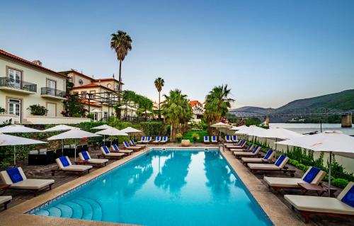 a swimming pool with lounge chairs and umbrellas at The Vintage House - Douro in Pinhão
