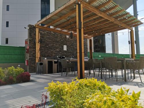 a patio with tables and chairs under a wooden pergola at Staybridge Suites - Irapuato by IHG in Irapuato
