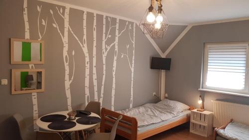 a bedroom with a bed and a tree mural at Pokoje InoSasino z basenem i sauną in Sasino
