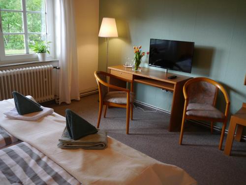 a hotel room with two beds and a desk with a television at Im Alten Bahnhof in Bergen