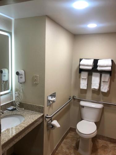 a bathroom with a toilet and a sink with towels at La Quinta by Wyndham Columbus - Grove City in Grove City