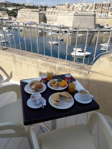 Kalkara的住宿－波爾圖德里奧別墅酒店，一张桌子上的一盘早餐食品,享有海港的景色