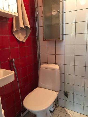 a bathroom with a white toilet and red tiles at Willa Strand in Kristiinankaupunki