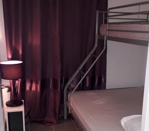 - une chambre avec 2 lits superposés et des rideaux rouges dans l'établissement F2 50m de la mer avec parking privé, à Valras-Plage