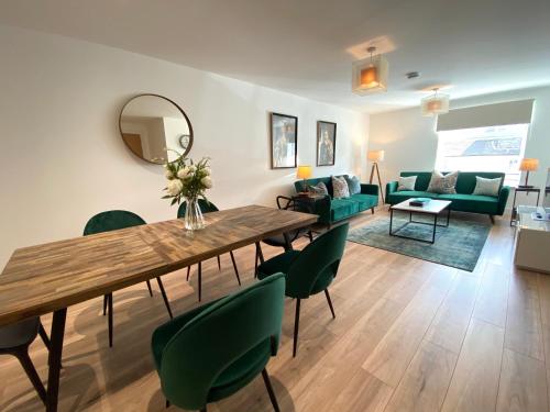 uma sala de estar com uma mesa de madeira e cadeiras verdes em High Street, Stylish City Centre Apartment, 3 Bed em Perth