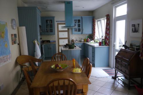 Period house on seafront, Bangor Co.Down في بانغور: مطبخ مع الدواليب الزرقاء وطاولة مع صحن من الفواكه عليها
