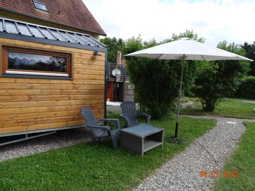 a patio with two chairs and an umbrella at Tiny-house in Wihr-au-Val