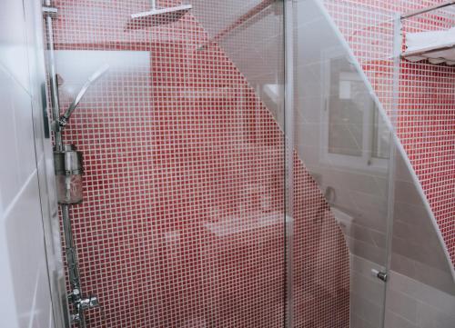 a red tiled shower with a glass door in a bathroom at ERES EMÉRITA "Apartamentos & Suites" in Merida