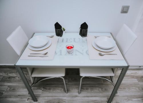 a white table with white plates and utensils on it at ERES EMÉRITA "Apartamentos & Suites" in Merida
