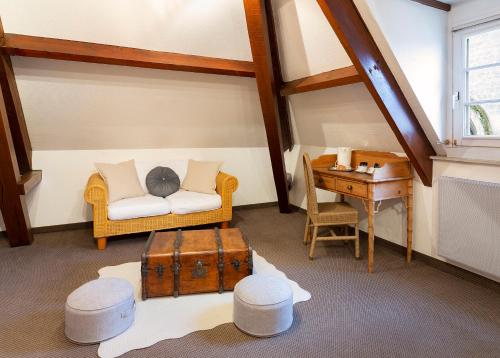 Cette chambre mansardée comprend un canapé, un bureau et une table. dans l'établissement HÔTEL JEAN DE BRUGES, à Saint-Riquier