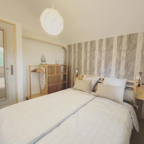 une chambre avec un grand lit avec des draps blancs dans l'établissement Cottage-Gite & Jacuzzi - Chez Flo & Marc, à Chouzy-sur-Cisse