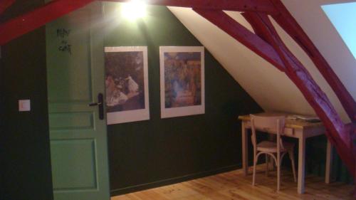 Cette chambre mansardée comprend une table et des photos sur le mur. dans l'établissement Les Gallerands, à Bessais-le-Fromental