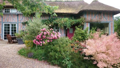 a brick house with a red door and some flowers at L'Escapade in Foulbec