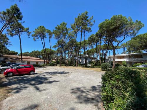a red car parked in a parking lot with trees at MaremMare Tuscany Apartments in Principina a Mare