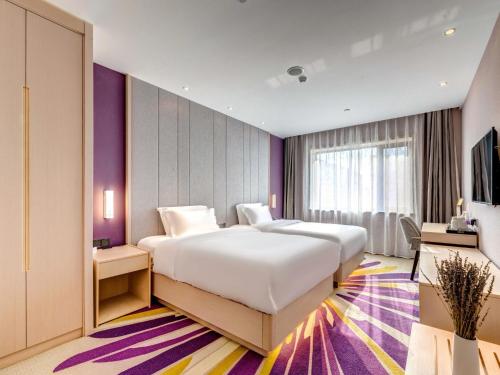 una camera da letto con un grande letto bianco e una parete viola di Lavande Hotel Tianjin Joy City Gulou Subway Station a Tianjin
