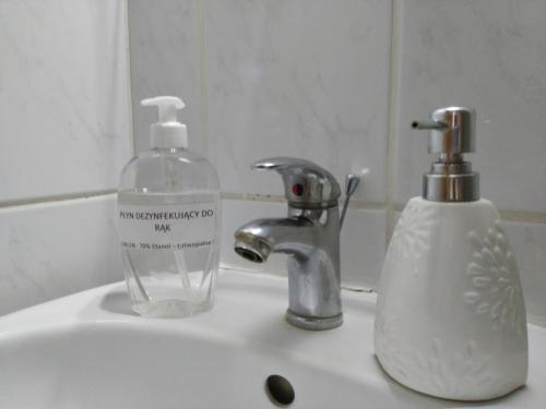 a bathroom sink with a soap dispenser and a bottle of soap at Iwona Hostel - Budget Rooms with Private Bathrooms in Sopot