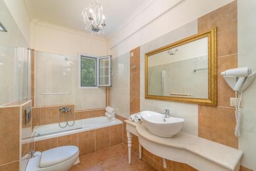 a bathroom with a sink and a tub and a toilet at Orion Hotel in Nydri