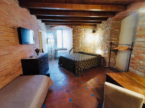 a room with a bed and a tv in a brick wall at Angolo Del Poeta in Bergamo