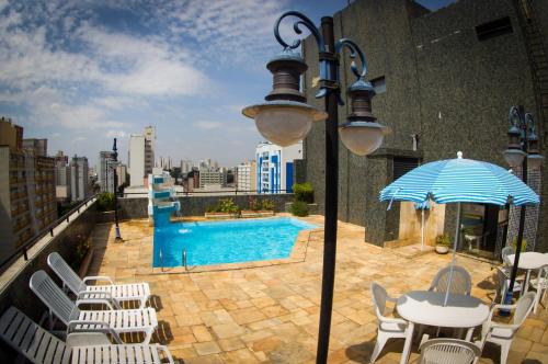 einen Balkon mit Pool, Tisch und Sonnenschirm in der Unterkunft LEON PARK HOTEL e CONVENÇÕES - Melhor Custo Benefício in Campinas