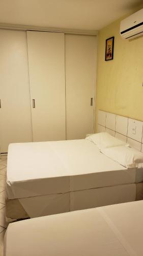 two beds in a room with white walls at Garvey Flats in Brasilia