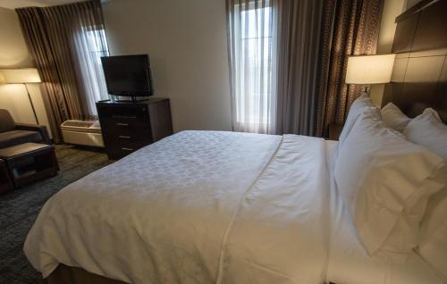 a hotel room with a white bed and a television at Staybridge Suites Silicon Valley - Milpitas by IHG in Milpitas
