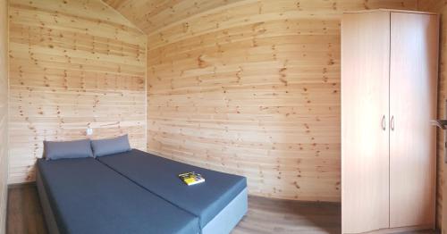 sypialnia z niebieskim łóżkiem w drewnianej ścianie w obiekcie Willa Aleksander w Rewalu