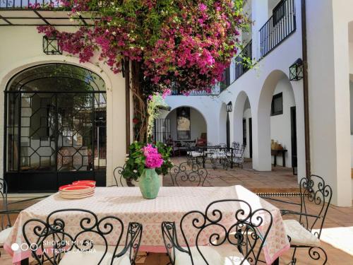 Lince Casa Rural في إل روثيو: طاولة وكراسي مع زهور وردية على الفناء