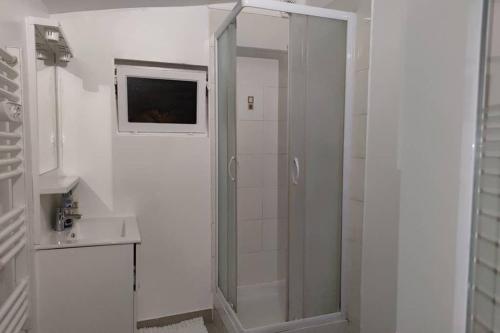 uma casa de banho branca com um chuveiro e um lavatório. em Super Appart ds pavillon, équipé, calme (Ref: KA0) em Montfermeil