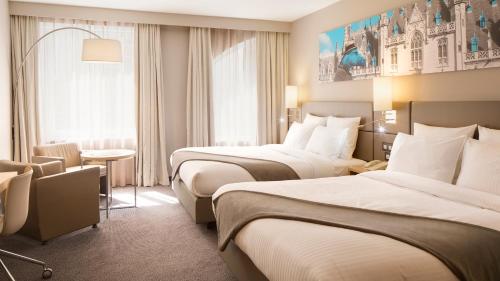 a hotel room with two beds and a table at Crowne Plaza Hotel Brugge by IHG in Bruges