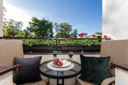 a table with a bowl of fruit and two glasses of wine at Apartamenty Vincent Sopot in Sopot