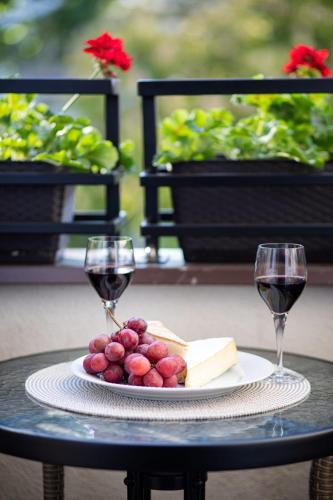 a plate of cheese and two glasses of wine on a table at Apartamenty Vincent Sopot in Sopot
