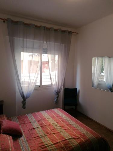 ein Schlafzimmer mit einem Bett und zwei Fenstern in der Unterkunft Ortensia - Sanremo Apartments in Sanremo