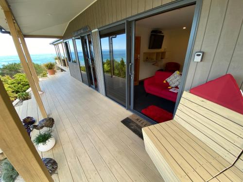 a balcony of a house with a red couch at Tasman Sea Retreat in Punakaiki