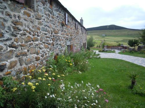 a stone building with flowers in front of it at Le Francillon in Les Estables