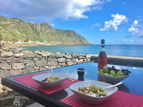 a table with two bowls of food and a bottle of wine at Vigia da Areia in São Lourenço