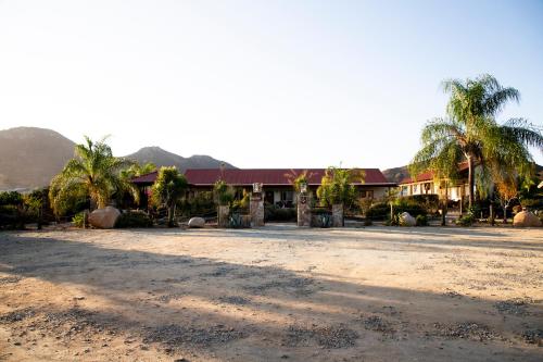 a house with palm trees and a dirt road at Terra del Valle Bed & Breakfast in Valle de Guadalupe