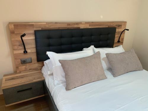 a large bed with a black headboard and two pillows at NerjaRooms in Nerja