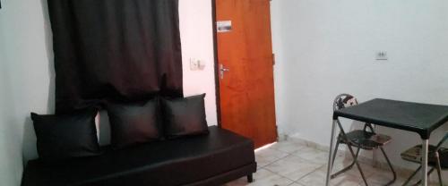 a room with a bed and a table and a door at VILLA GARDEN - Suites in Maresias